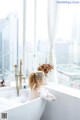 A woman sitting in a bathtub in front of a window.