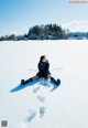 A woman sitting in the middle of a snow covered field.