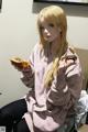 A woman sitting on a bed eating a sandwich.