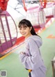 A woman in a purple hoodie standing in front of a ferris wheel.