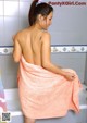 A woman in a pink towel sitting in a bathtub.