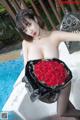 A woman holding a bunch of red roses next to a pool.