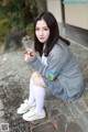 A young woman sitting on the ground holding a flower.