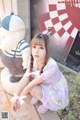 A young woman sitting on the ground next to a statue.